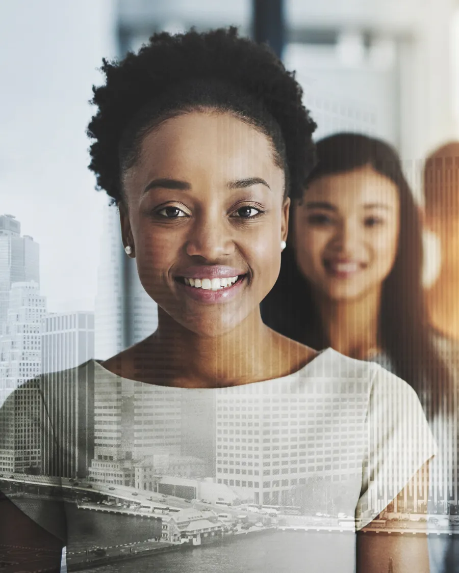 A smiling young professional in front of a city skyline, her colleagues beside her.