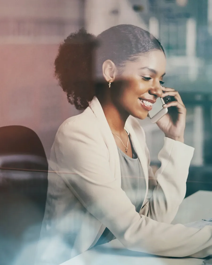 A businesswoman on the phone at her desk, smiling.